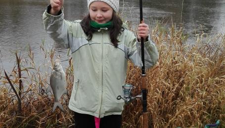 Väike tüdruk poseerib kalaga, mille ta on püüdnud