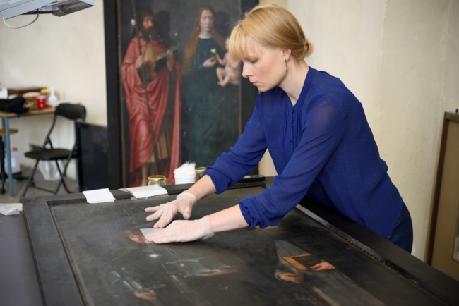 KUMU maalide konservaator Johanna Lamp eemaldamas maalitahvlilt lakikihti. Autor: Stanislav Stepaško