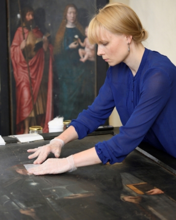 KUMU maalide konservaator Johanna Lamp eemaldamas maalitahvlilt lakikihti. Autor: Stanislav Stepaško